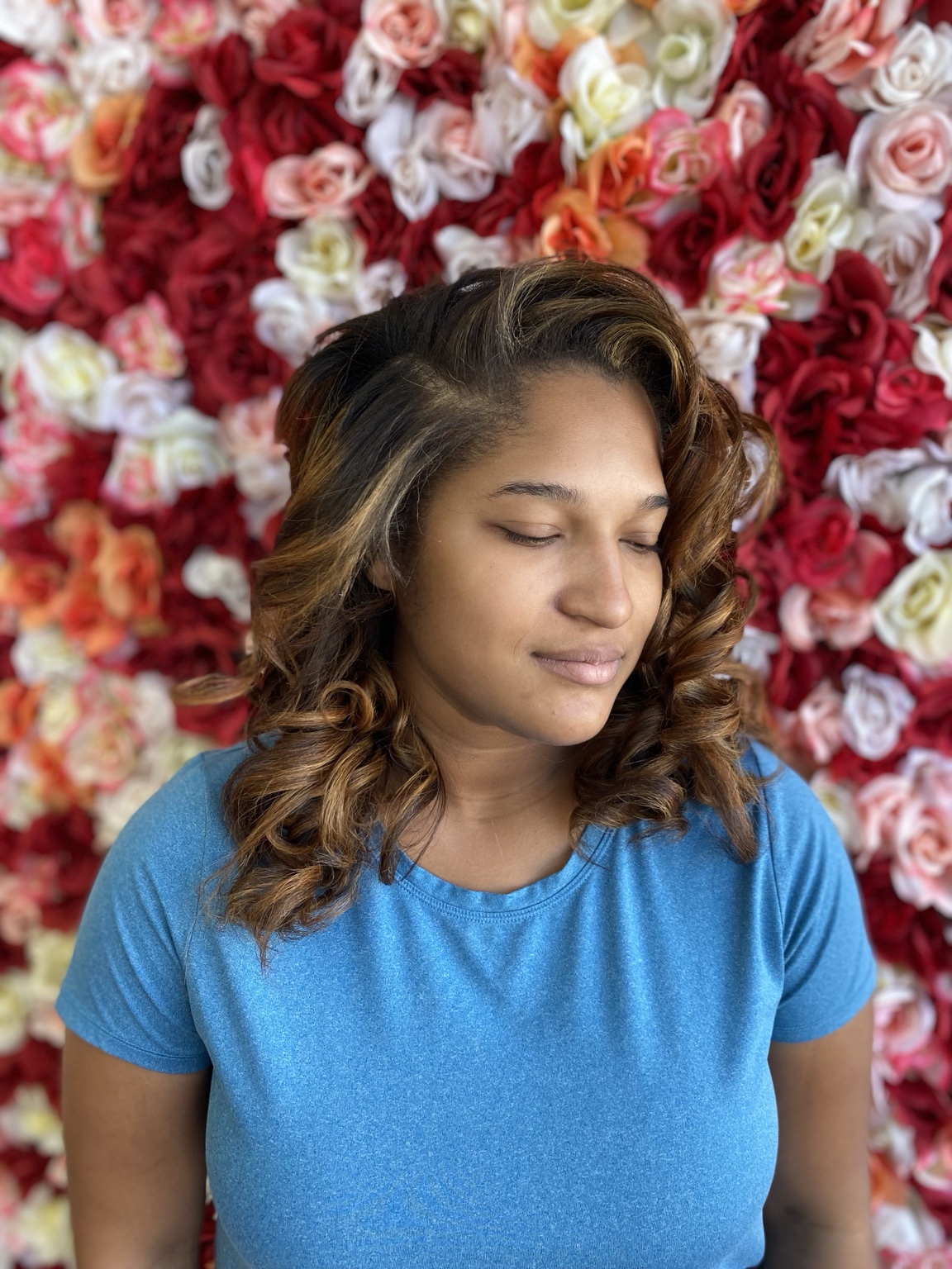 Client wearing healthy dimensional curls with warm caramel highlights